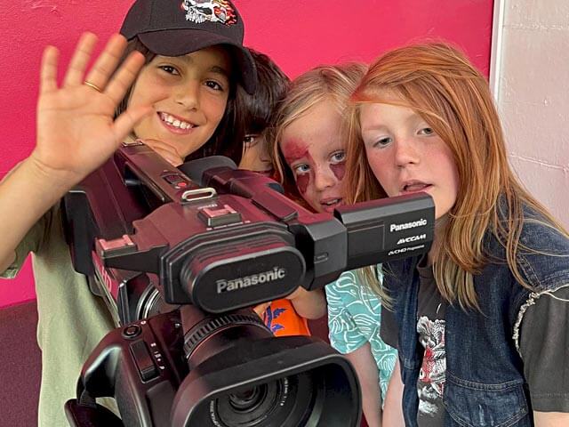 a group of happy students using a large video camcorder